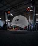 Generated with Kive.ai - Create a premium cinematic product photo of product using Gym as the exact unchanged background. Place the cap levitating in the empty foreground_ exactly in the horizontal center of .jpg